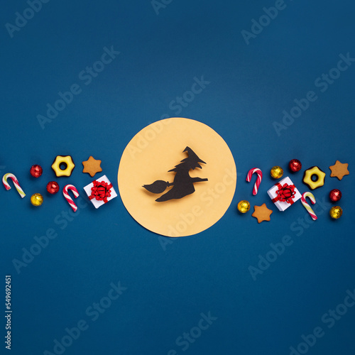 Italian Epiphany day concept. Witch Befana flying on broomstick, moon, stars and christmas sweets on dark blue background. photo