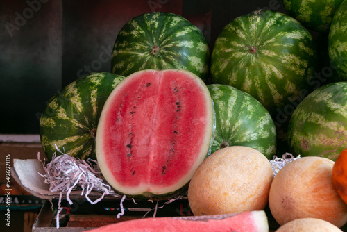 Watermelons and melons lie on the counter in the market. Sale of ripe and fresh vegetables and fruits at a large farmers' market. Seasonal fair. Close-up