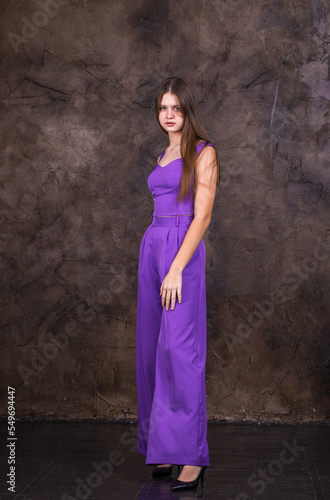 Portrait of a young beautiful brunette girl in purple pantsuit © Andrey_Arkusha