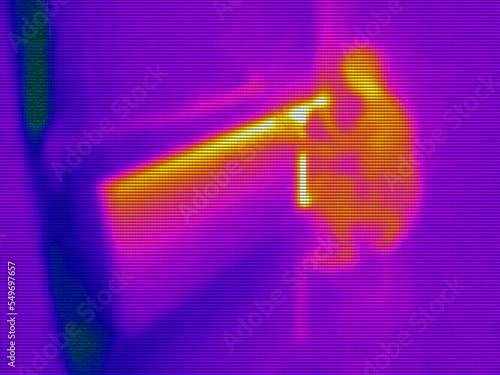 infrared thermal photography of a young woman adjusting the temperature on a room heating radiator photo