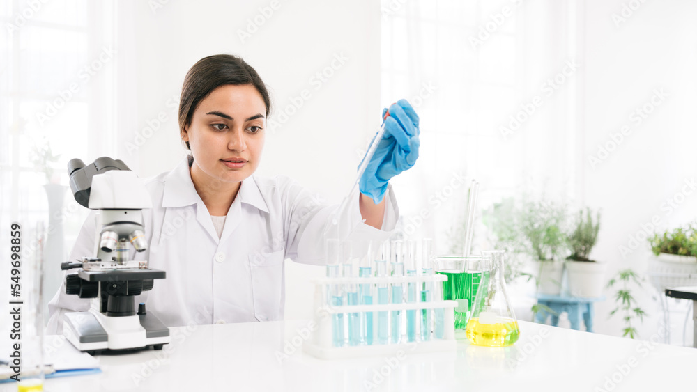 Middle East woman scientist researcher use a lab dropper to drip a substance into a test tube for analysis of liquids in the lab. Scientist working with a dropper and a test tube. Middle East woman scientist researcher use a lab dropper to drip a substance into a test tube for analysis of liquids in the lab. Scientist working with a dropper and a test tube.