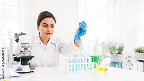 Middle East woman scientist researcher use a lab dropper to drip a substance into a test tube for analysis of liquids in the lab. Scientist working with a dropper and a test tube.