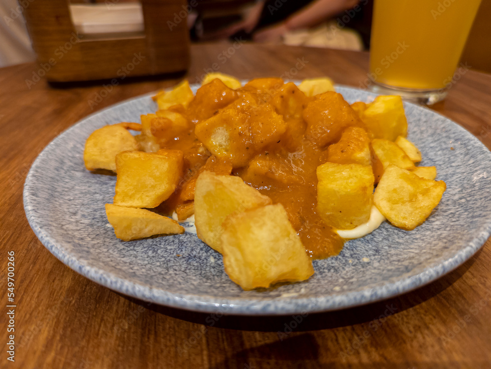 Typical Spanish dish called patatas bravas, fried tubers with red spicy sauce containing onion, paprika, oregano, chilli Typical Spanish dish called patatas bravas, fried tubers with red spicy sauce containing onion, paprika, oregano, chilli
