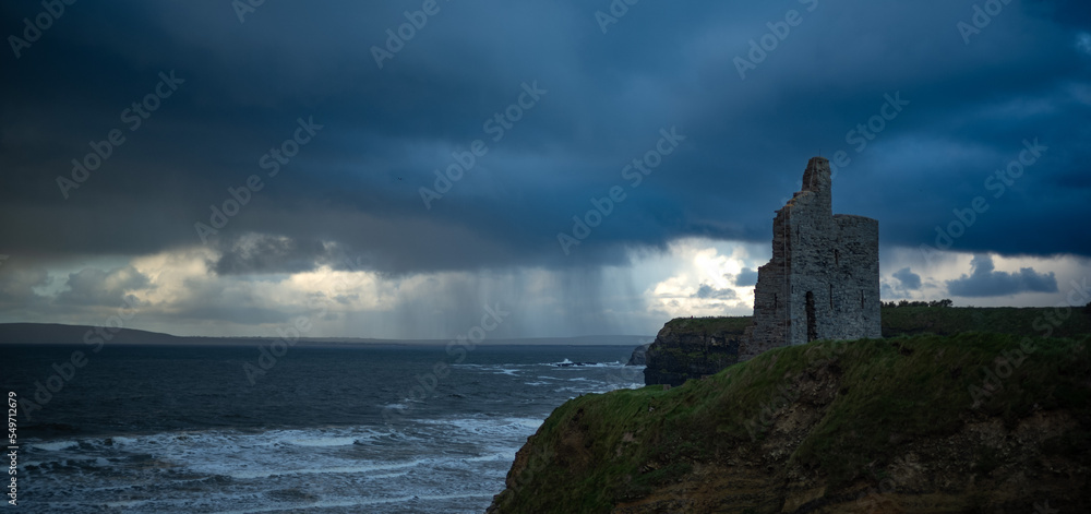 Ruins of Ballybunion Castle on the west coast of Ireland, dark dramatic stormy skies background.