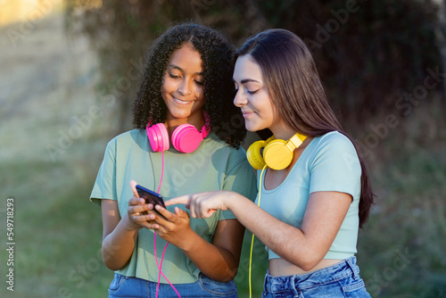 Happy friends looking the smartphone and colorful headphones