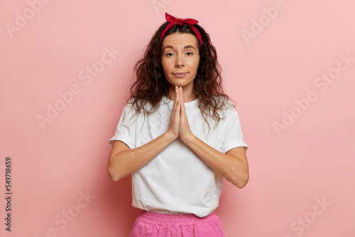Leinwand Poster Pretty young lady beg with cute face, stands isolated over pink background