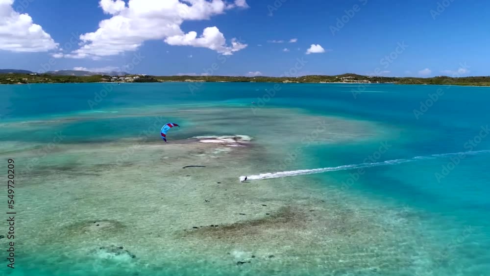 Kitesurfing in turquoise water of tropical beach paradise in warm waters at bright sunny day. Aerial view Kitesurfing in turquoise water of tropical beach paradise in warm waters at bright sunny day. Aerial view