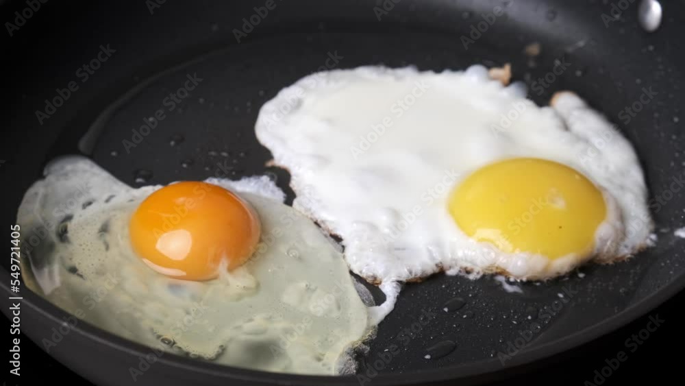 Frying egg in black frying pan. Breakfast preparation process. Frying egg in black frying pan. Breakfast preparation process.