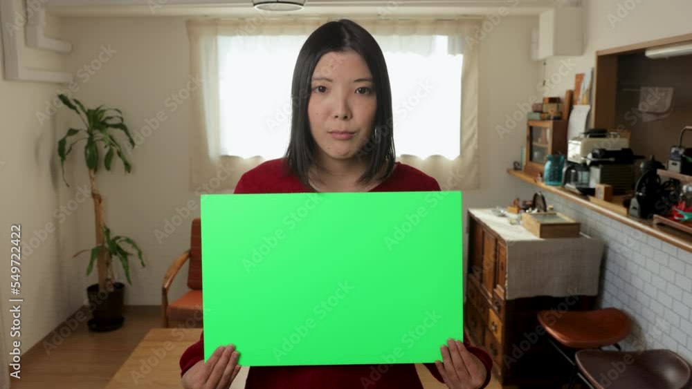 Young asian woman holding green board for chromakey edit at home. Serious, Protest, Appeal, Anger. Young asian woman holding green board for chromakey edit at home. Serious, Protest, Appeal, Anger.