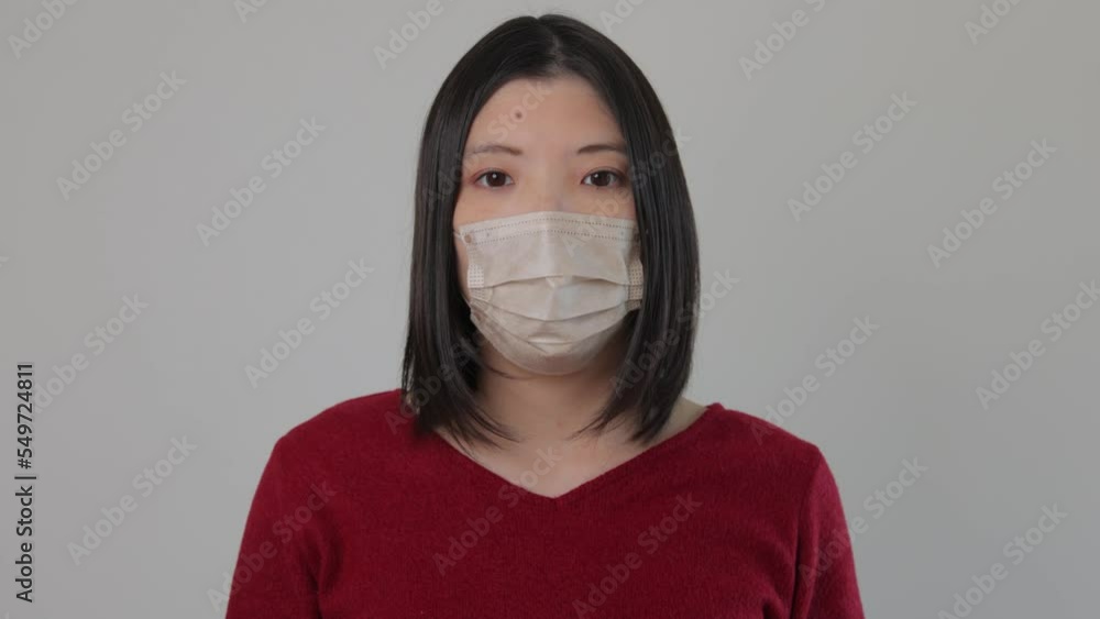 Asian young woman standing still with her mask on and stars the camera. Reluctant, Tired, Disappointed. Asian young woman standing still with her mask on and stars the camera. Reluctant, Tired, Disappointed.