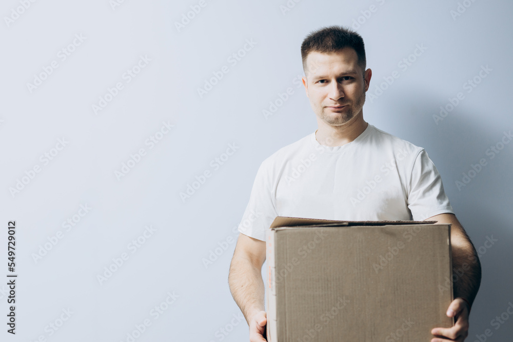 European guy is holding a cardboard box for parcels. Courier with box ordered online. Person holding cardboard box in the hands. Mail delivery and post service, online shopping, e commerce concept. European guy is holding a cardboard box for parcels. Courier with box ordered online. Person holding cardboard box in the hands. Mail delivery and post service, online shopping, e commerce concept.