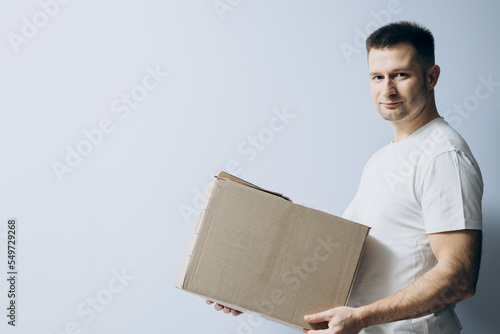 European guy is holding a cardboard box for parcels. Courier with box ordered online. Person holding cardboard box in the hands. Mail delivery and post service, online shopping, e commerce concept.