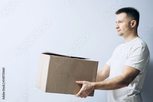 European guy is holding a cardboard box for parcels. Courier with box ordered online. Person holding cardboard box in the hands. Mail delivery and post service, online shopping, e commerce concept.
