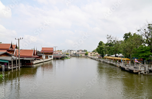 BANGKOK, THAILAND - NOVEMBER 20, 2022 : Wooden houses, Thai houses and buildings along the Chao Phraya River with white clouds and blue sky background, Town Ayutthaya Waterfront, Thailand.