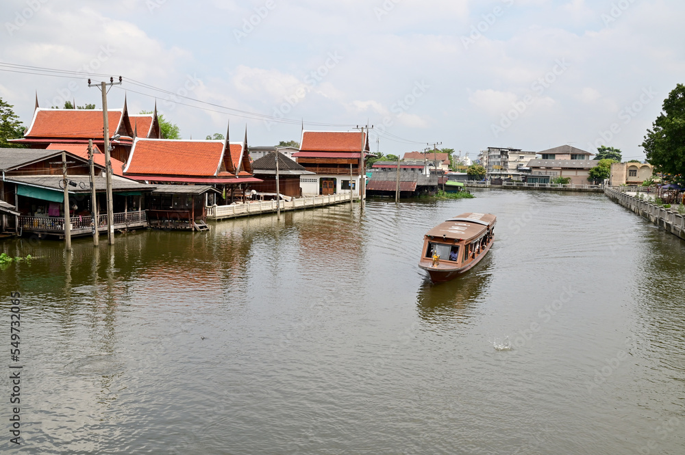 BANGKOK, THAILAND - December 02, 2022 : Tourist Passenger Boat leading tourists to view the houses along the canal and the ways of villagers along the canal in the Chao Phraya River Canal.