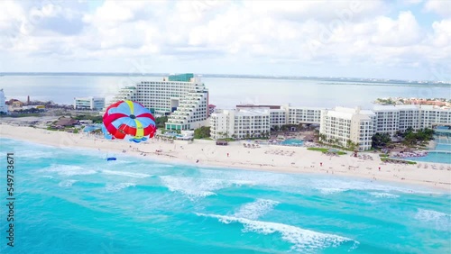Parasailing aerial view. A couple paraskiing at tropical beach in bright day. 