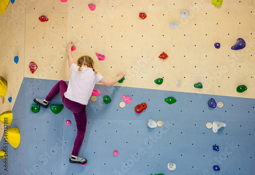 Girl child do bouldering known as free climbing exercise indoors leisure activity.