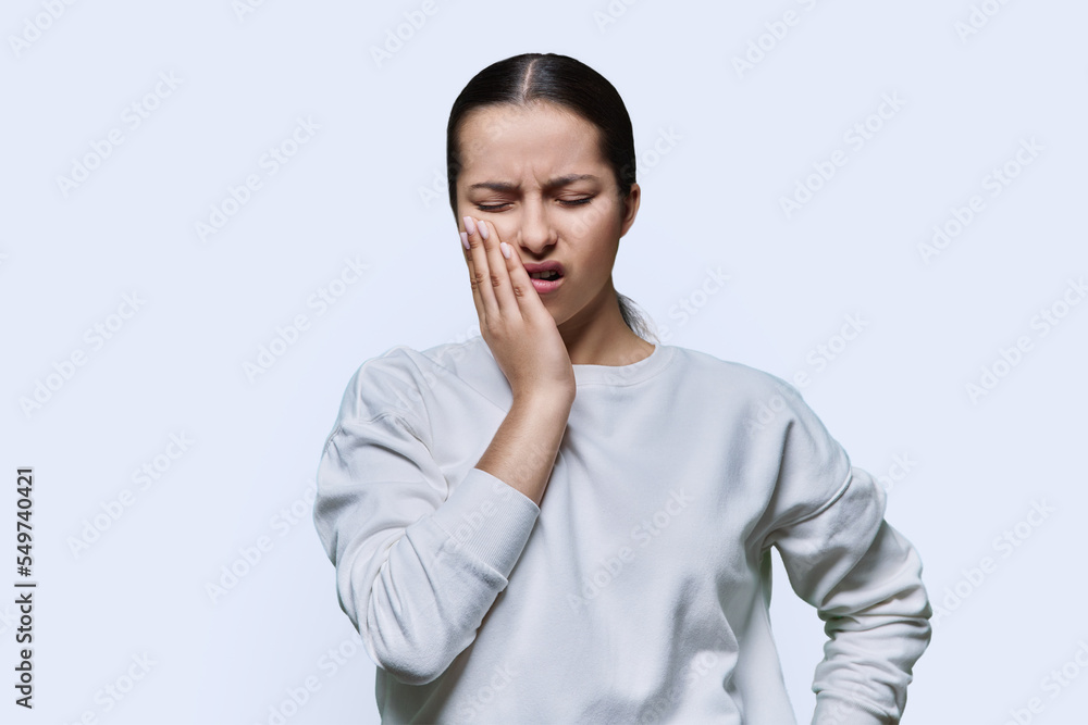Teenage girl having toothache, on white studio background Teenage girl having toothache, on white studio background