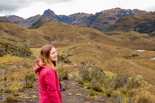 A smiley female hiker enjoying a spectacular view in the Cajas National Park in the highlands of Ecuador, tropical Andes.