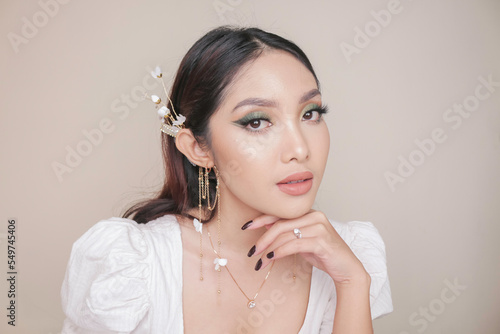 Close-up beauty face of Asian young model wearing ear accessories or ear cuff. Green eyes make-up look. Skincare beauty facial treatment, spa, female health concept.