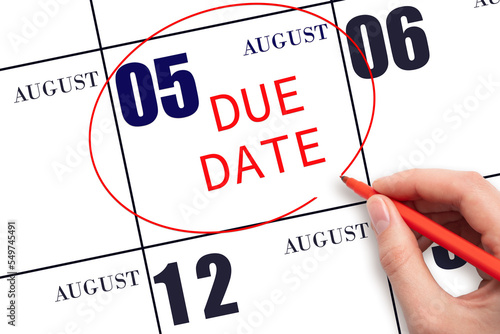 5th day of August. Hand writing text DUE DATE on calendar date August 5 and circling it. Payment due date. Business concept. Summer month, day of the year concept. photo