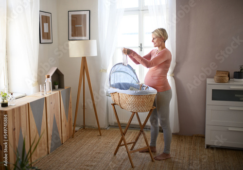 Happy pregnant woman looking at little clothes for her baby.