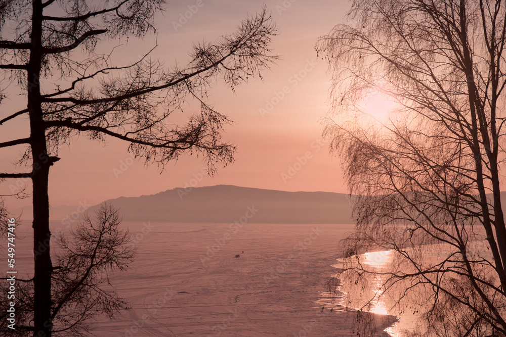 Silhouettes of Trees Against the Backdrop of a Sunset on a Frozen Winter Lake. Silhouettes of Trees Against the Backdrop of a Sunset on a Frozen Winter Lake.