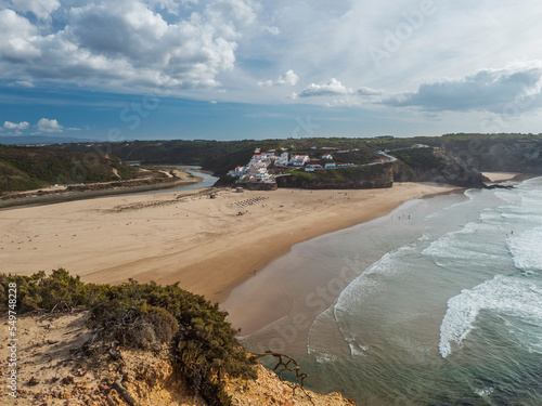 Panoramic view of Praia de Odeceixe Mar Surfer beach with golden sand, atlantic ocean waves, river bend and white houses of Odeceixe village. Rota Vicentina coast, Odemira, Portugal. photo