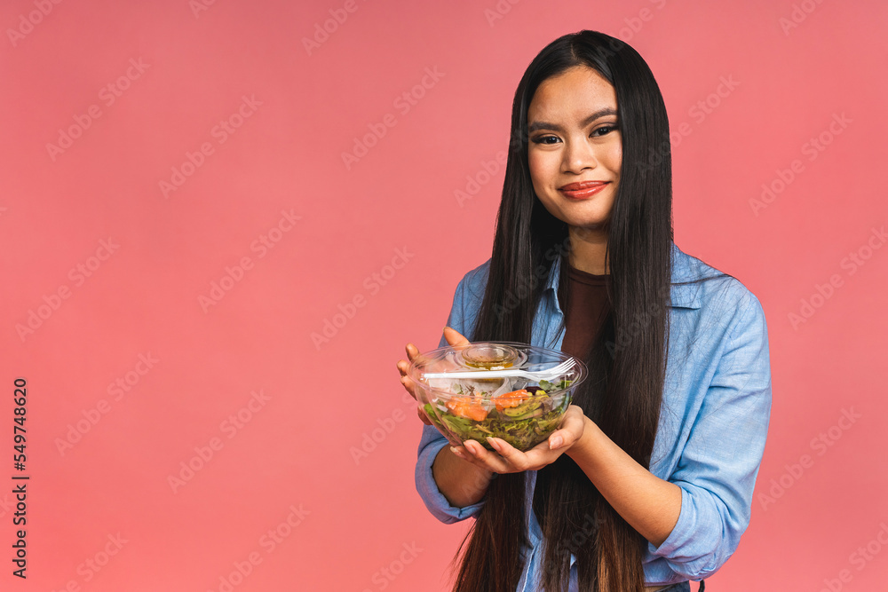 Clean eating diet concept. Asian woman holding vegeterian salad or bowl in take away container. Close up, copy space, top view, isolated over pink background. Clean eating diet concept. Asian woman holding vegeterian salad or bowl in take away container. Close up, copy space, top view, isolated over pink background.