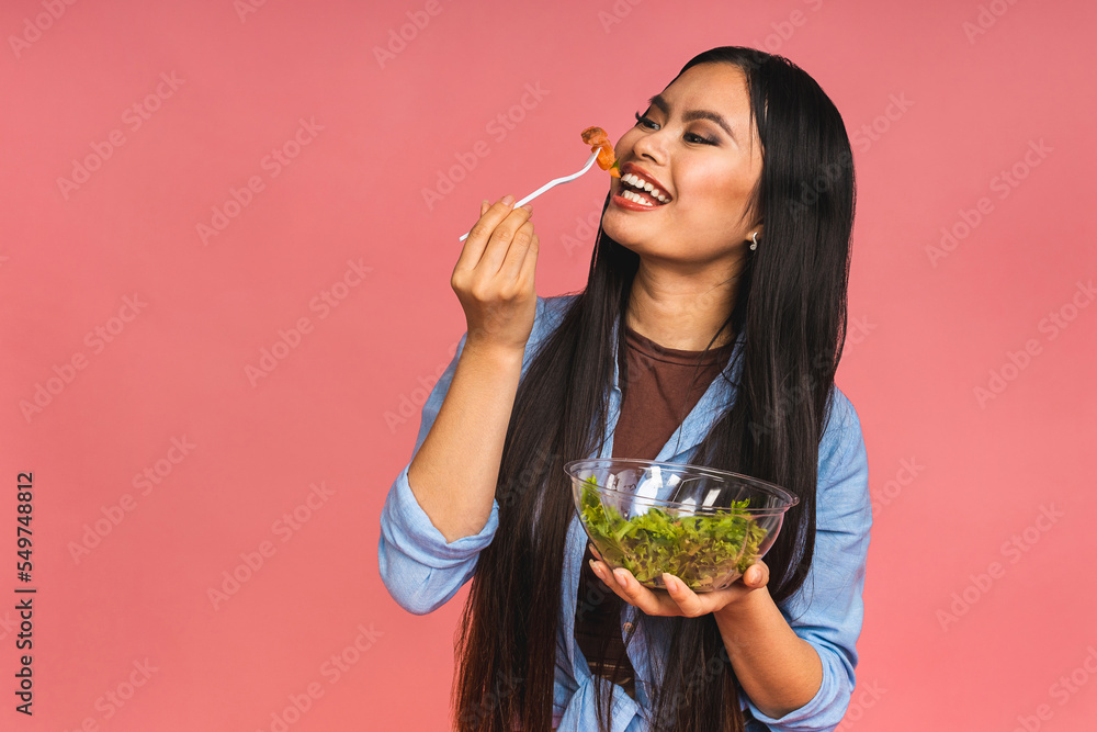 Clean eating diet concept. Asian woman holding vegeterian salad or bowl in take away container. Close up, copy space, isolated over pink background. Clean eating diet concept. Asian woman holding vegeterian salad or bowl in take away container. Close up, copy space, isolated over pink background.