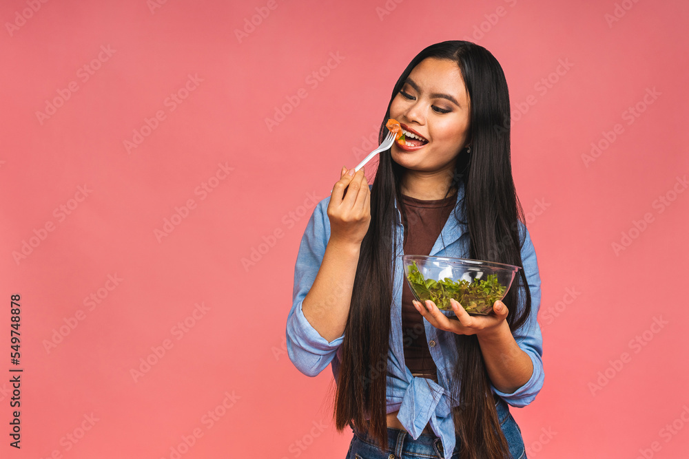 Clean eating diet concept. Asian woman holding vegeterian salad or bowl in take away container. Close up, copy space, isolated over pink background. Clean eating diet concept. Asian woman holding vegeterian salad or bowl in take away container. Close up, copy space, isolated over pink background.