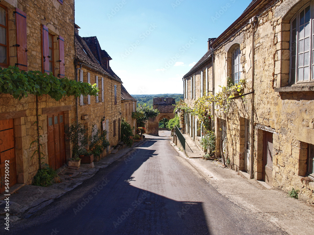 Majestic Bastide of Domme and medieval town of Périgord Noir - Narrow street with old yellow stone perigordian houses before Delbos Gate (Porte de Delbos)