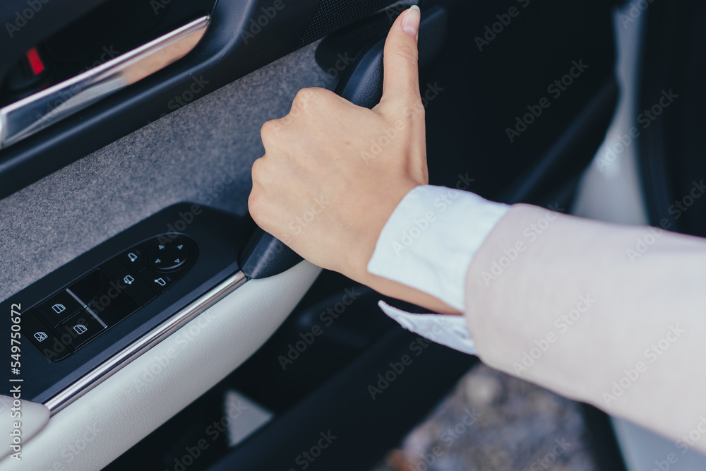 Close-up of young woman's hand closing car doors.