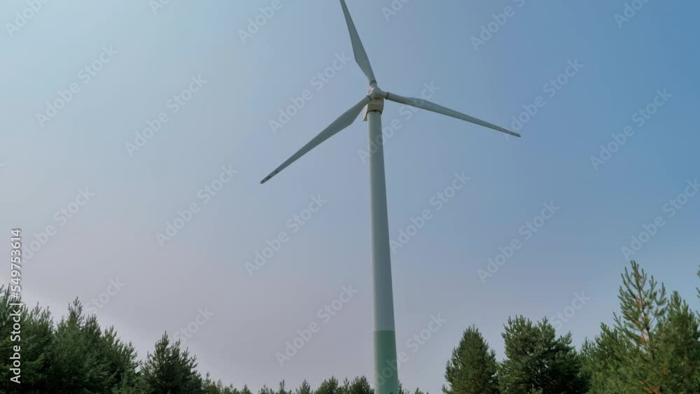 Bottom up view of a huge windmill rotating. Clear sunny day. Wind power turbine generating renewable energy. Alternative energy concept Bottom up view of a huge windmill rotating. Clear sunny day. Wind power turbine generating renewable energy. Alternative energy concept