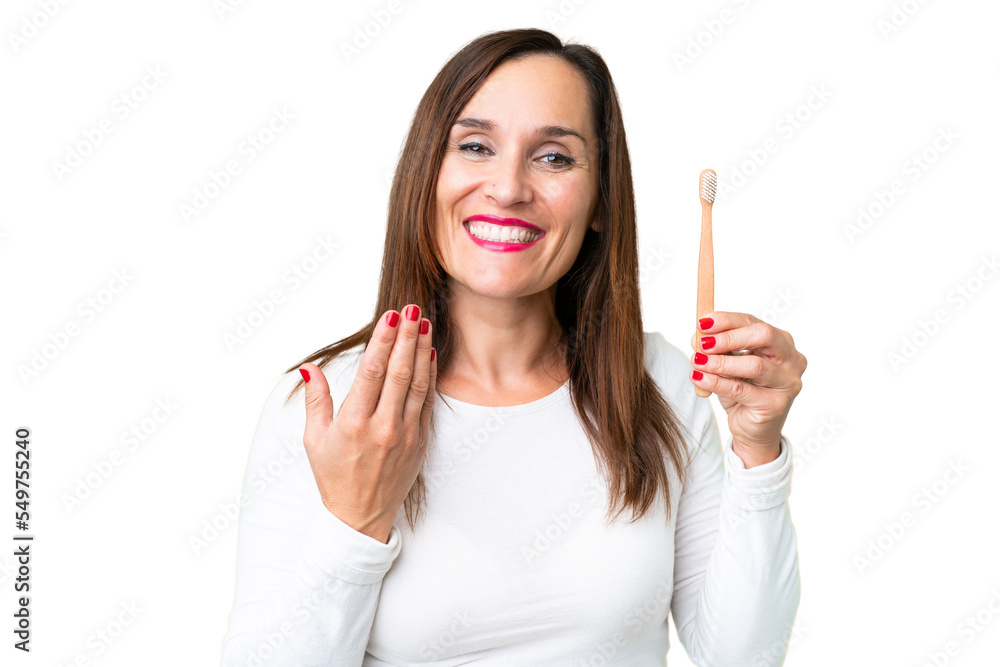 Middle age woman brushing teeth over isolated chroma key background inviting to come with hand. Happy that you came Middle age woman brushing teeth over isolated chroma key background inviting to come with hand. Happy that you came