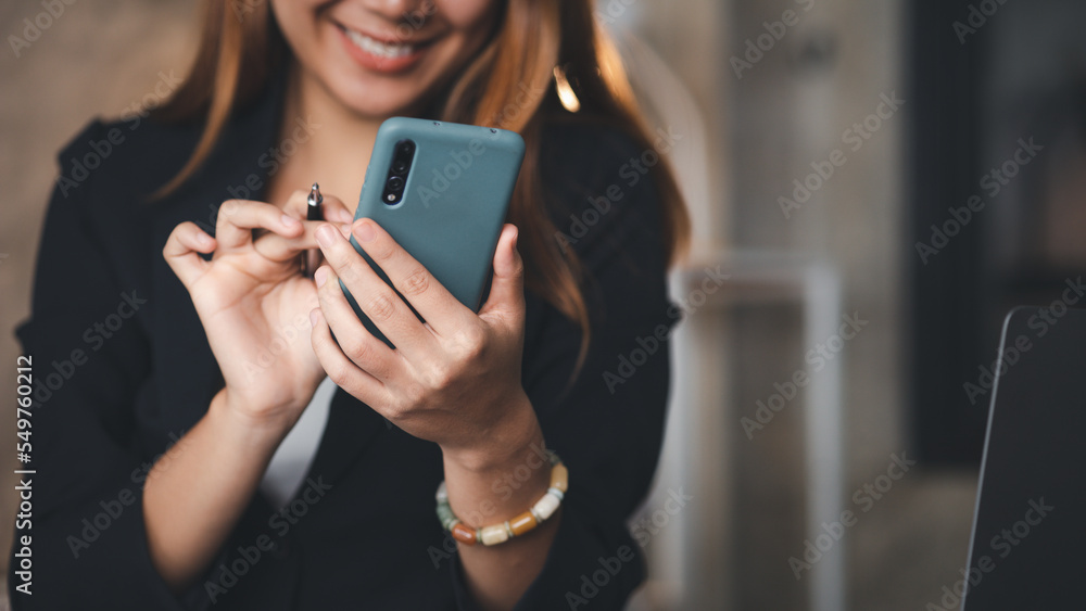Beautiful Asian woman playing mobile phone in her break from work, she is a marketing manager of a startup company, female leader, supervisor, ceo. Female Leadership Concept. Beautiful Asian woman playing mobile phone in her break from work, she is a marketing manager of a startup company, female leader, supervisor, ceo. Female Leadership Concept.