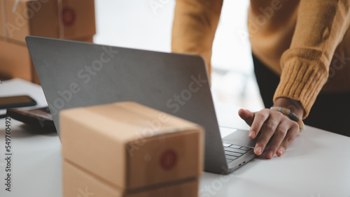 A business owner opens an online store, she is checking orders from customers, sending goods through a courier company, concept of a woman opening an online business.