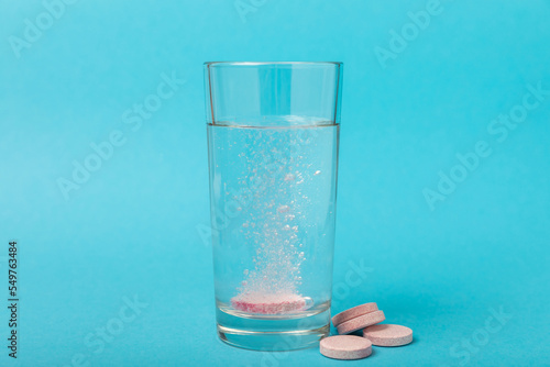 Effervescent tablet in a glass of water on a blue background. Vitamins. Health concept. Immunity drug. Space for copy. Space for text.