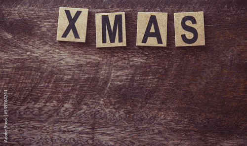 The letters of the abbreviation of the word christmas on a wooden background.