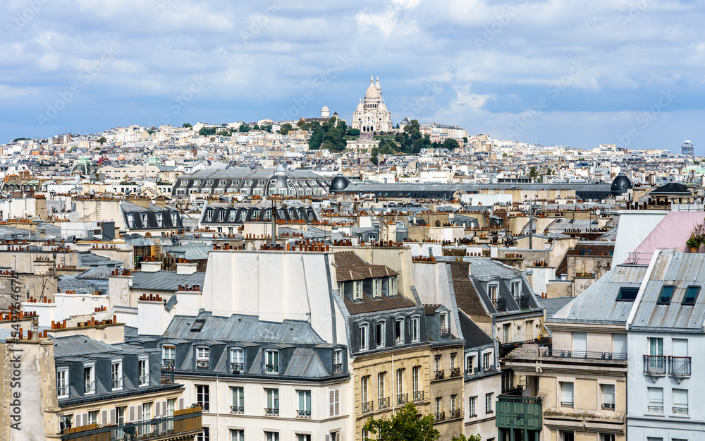 Panoramic aerial view of Paris, old historical building in the foreground, Montmartre Hill and Basilica of Sacre Coeur in the background. France.