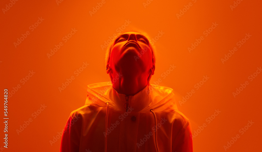 Young informal woman with closed eyes in neon orange studio Young informal woman with closed eyes in neon orange studio