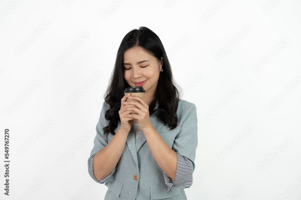 Portrait of a smiling asian businesswoman carrying cup of coffee to go while standing isolated over white background. Portrait of a smiling asian businesswoman carrying cup of coffee to go while standing isolated over white background.