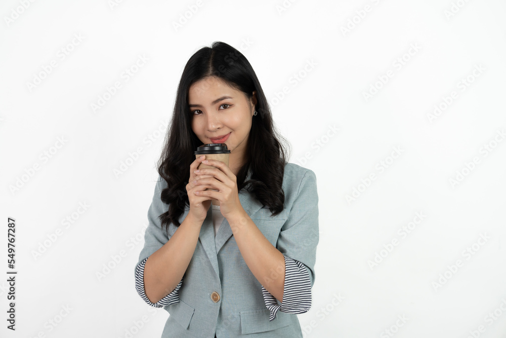 Portrait of a smiling asian businesswoman carrying cup of coffee to go while standing isolated over white background.