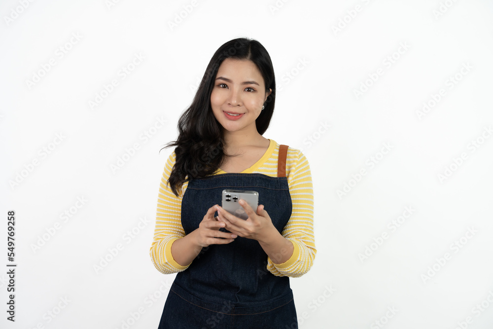 Portrait Charming young Asian businesswoman owner wearing an apron holding smartphone isolated on white background. Looking at the camera. Portrait Charming young Asian businesswoman owner wearing an apron holding smartphone isolated on white background. Looking at the camera.