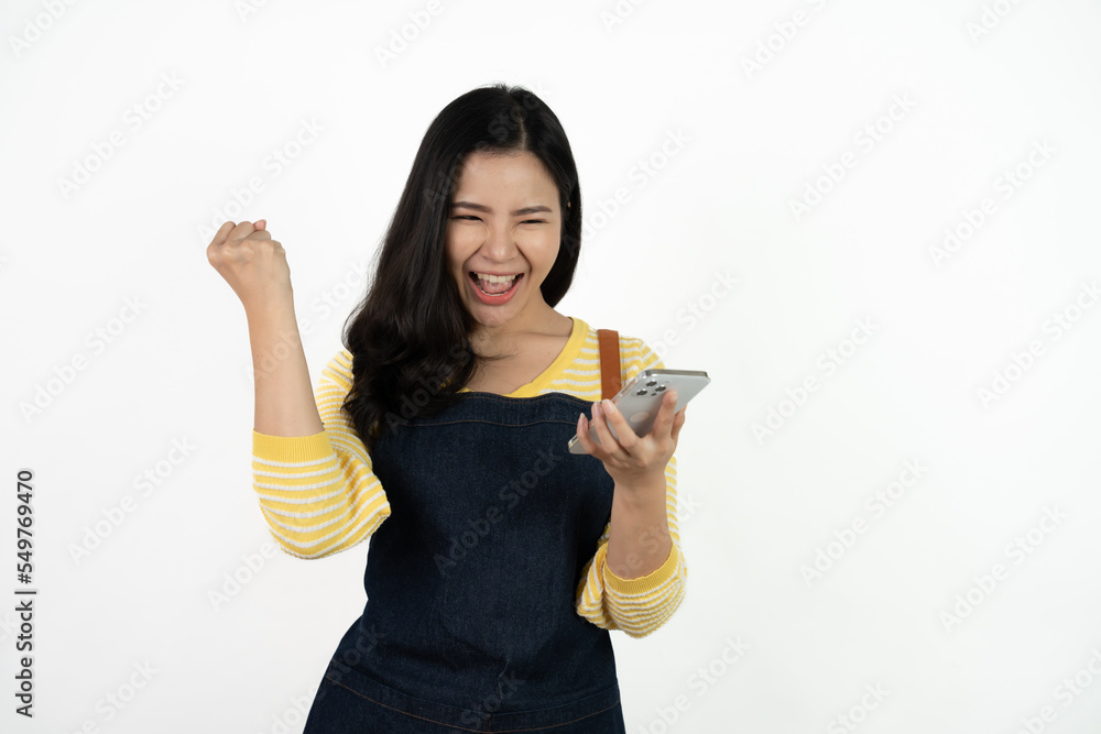 Portrait Charming young Asian businesswoman owner wearing an apron holding smartphone isolated on white background. Looking at the camera. Portrait Charming young Asian businesswoman owner wearing an apron holding smartphone isolated on white background. Looking at the camera.