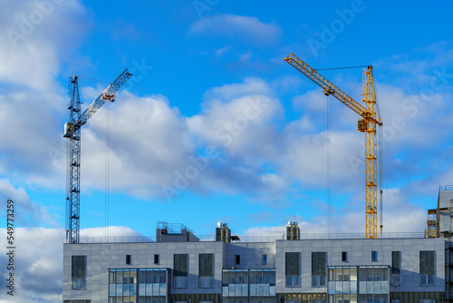 Construction cranes on construction site of apartment buildings in autumn sky