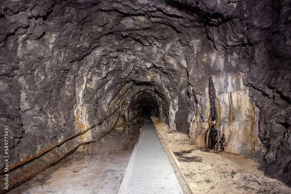 Obraz premium Underground abandoned white calcite marble ore mine shaft tunnel gallery passage with rails