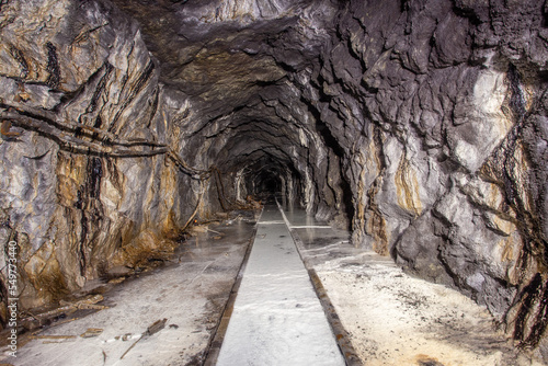 Underground abandoned white calcite marble ore mine shaft tunnel gallery passage with rails