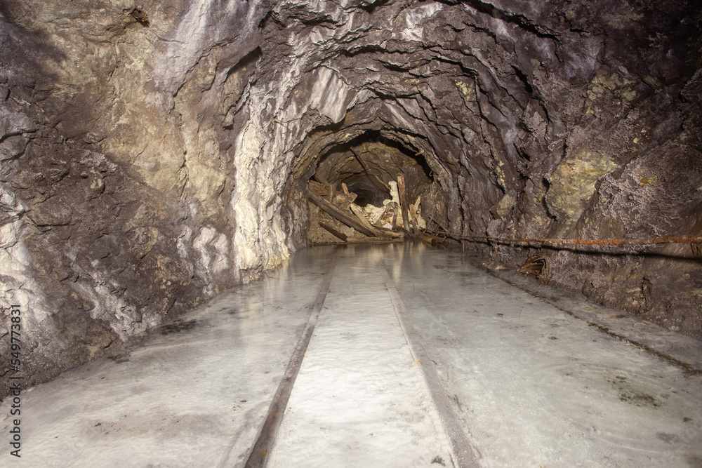 Underground abandoned gold iron ore mine shaft tunnel gallery passage with rails