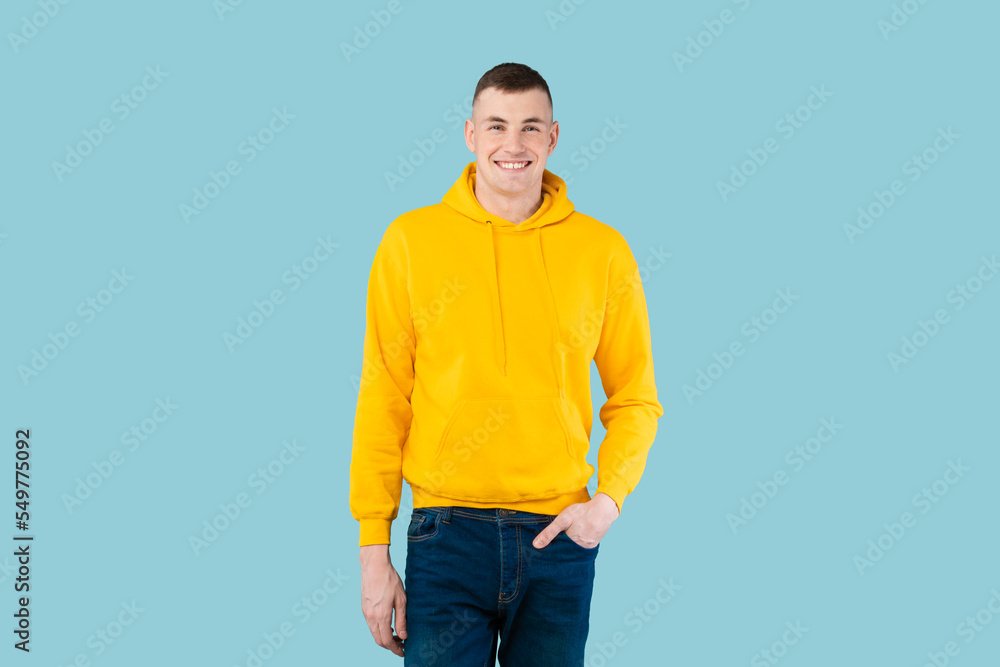 Happy handsome man posing with hand in pocket and smiling at camera on blue studio background, copy space Happy handsome man posing with hand in pocket and smiling at camera on blue studio background, copy space